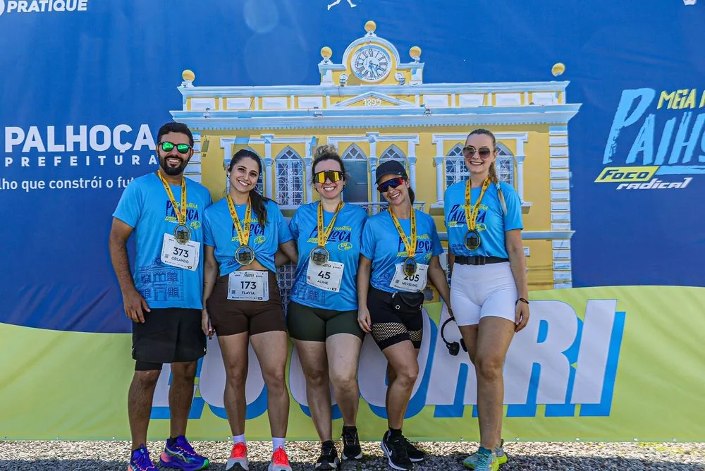 Grupo de atletas com a camiseta da prova diante do Paço Municipal