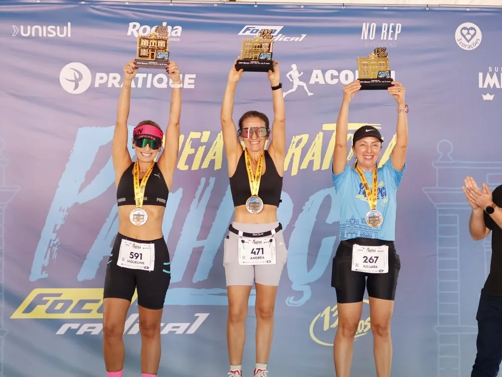Pódio com atletas erguendo troféus